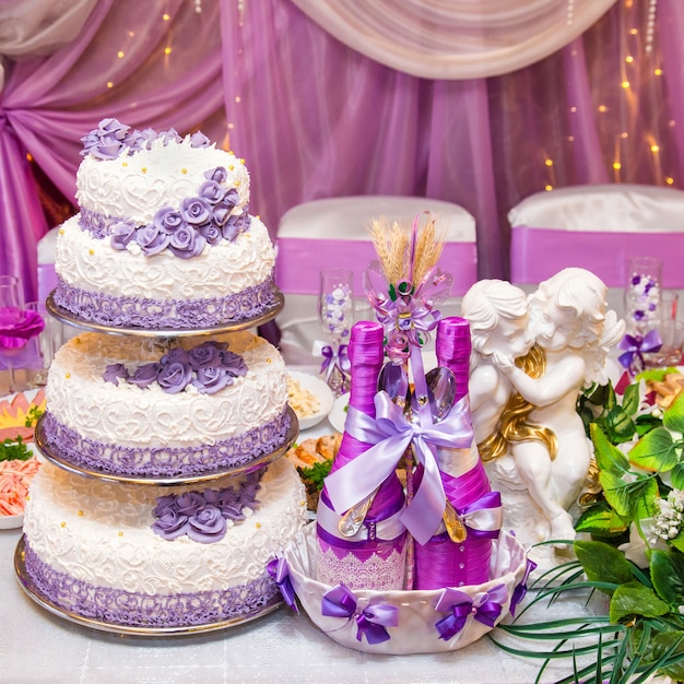 Pastel y dos botellas de vino en una mesa de boda decorada.