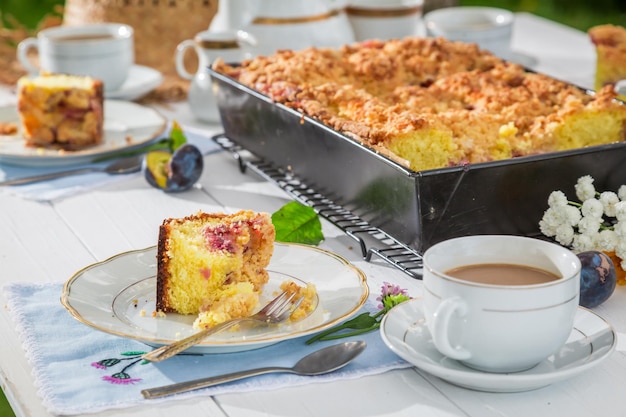 Pastel dulce con ciruela servido con café en el jardín.