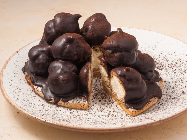 Pastel dulce un croquembouche de profiteroles con nata y rociado con chocolate