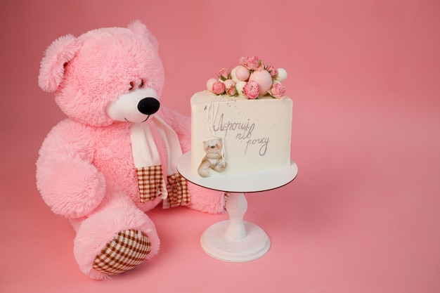 Foto pastel dulce y juguete de oso de peluche para niños sobre fondo rosa para cumpleaños