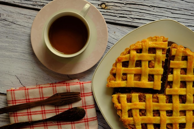 Un pastel es un plato horneado que contiene varios ingredientes. tarta de piña entera y una taza de té.