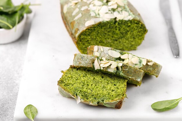 Pastel de espinacas con almendras laminadas cortadas en tablero de mármol Bizcocho Fondo gris Pastel verde