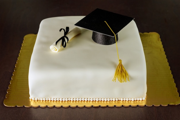 Pastel de fondant de graduación con decoración de sombrero y diploma para fiesta.