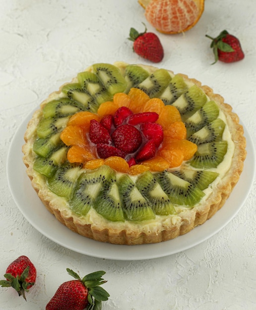 Pastel de frutas dulces con fresa, kiwi y naranjas