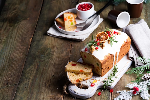 Pastel de frutas espolvoreado con glaseado, nueces, granos de granada y naranja seca de madera vieja. Pastel casero de Navidad e Invierno