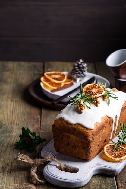 Pastel de frutas espolvoreado con glaseado, nueces y naranja seca en madera vieja. Pastel casero de Navidad e Invierno