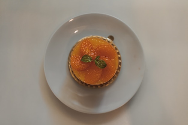 Pastel de frutas de naranja en una taza servido en un plato blanco