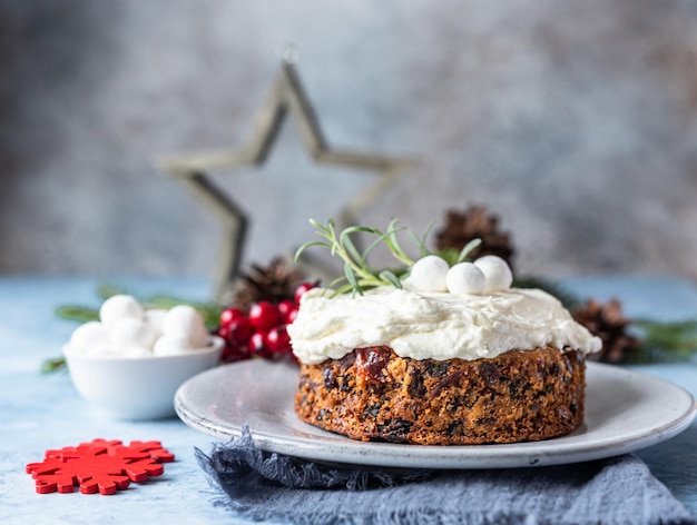 Pastel de frutas navideño o budín decorado con glaseado de romero y arándanos. Panadería tradicional