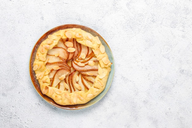 Pastel de galette de pera casero con hojas de almendras y peras verdes maduras frescas