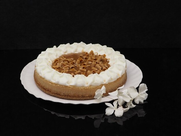 Pastel de galleta redonda con crema batida de caramelo y chocolate aislado sobre fondo negro