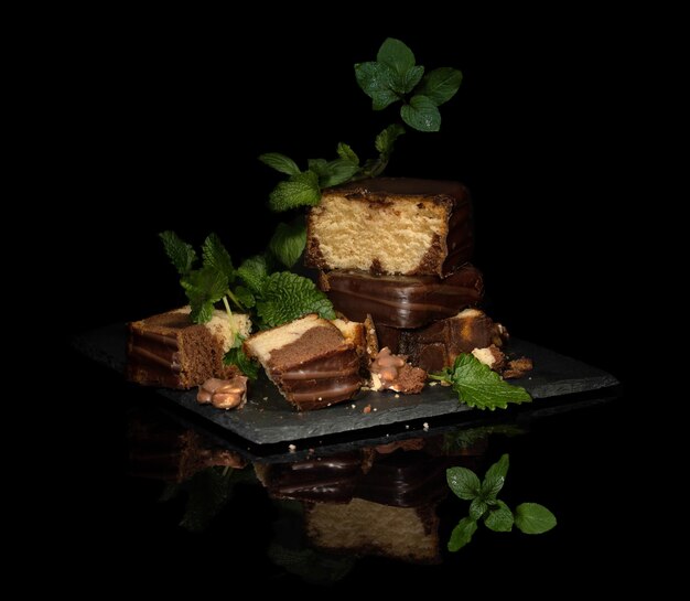 pastel de galletas de miel y chocolate cortado en porciones, hojas de menta sobre un fondo negro