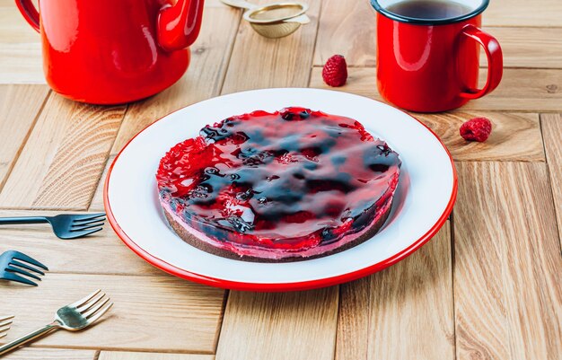 Pastel con gelatina de bayas con arándanos y frambuesas sobre una mesa de madera