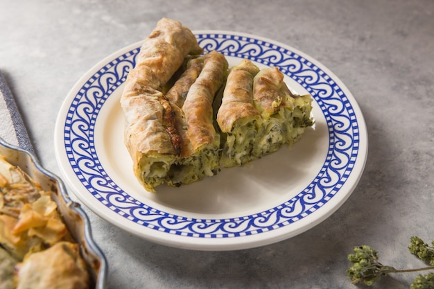 Pastel griego spanakopita sobre fondo de hormigón. Ideas y recetas para tarta de espinacas vegetariana o vegana de hojaldre cortado en rodajas