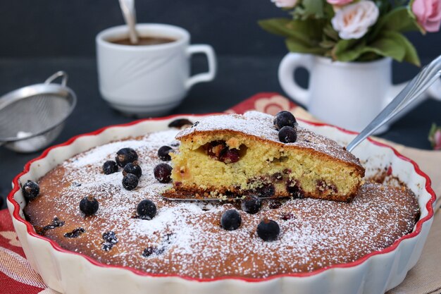 Pastel de grosella negra en forma de cerámica con un trozo de pastel cortado