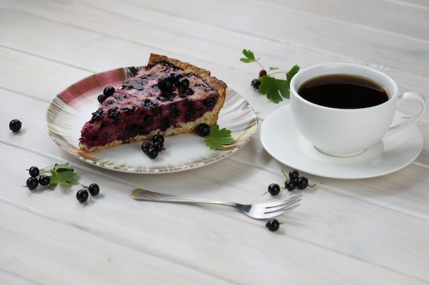 Pastel horneado con bayas de temporada y una taza de café sobre fondo de madera