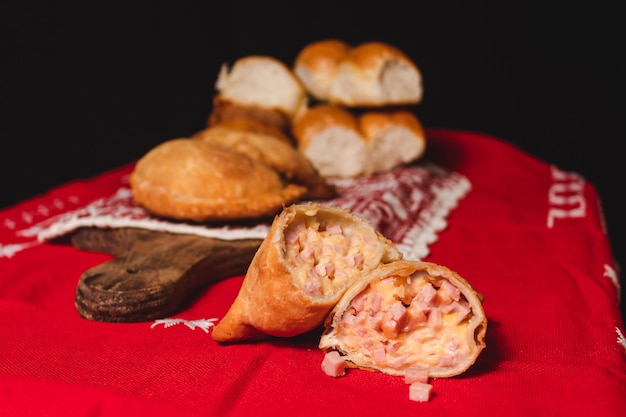 Pastel de jamón y queso cortado por la mitad sobre un paño rojo.