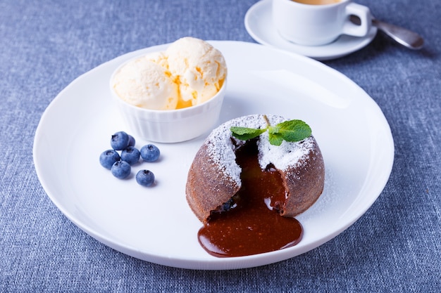 Pastel de lava con relleno de goteo Pastel de fondant de chocolate con helado de vainilla arándanos menta