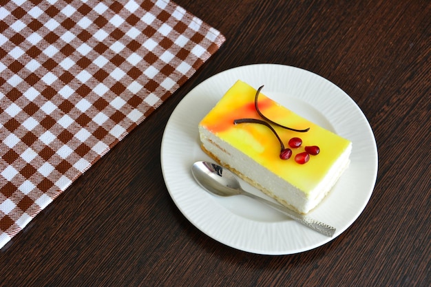 pastel de limón decorado con chocolate y semillas de granada en un plato sobre una mesa de madera oscura