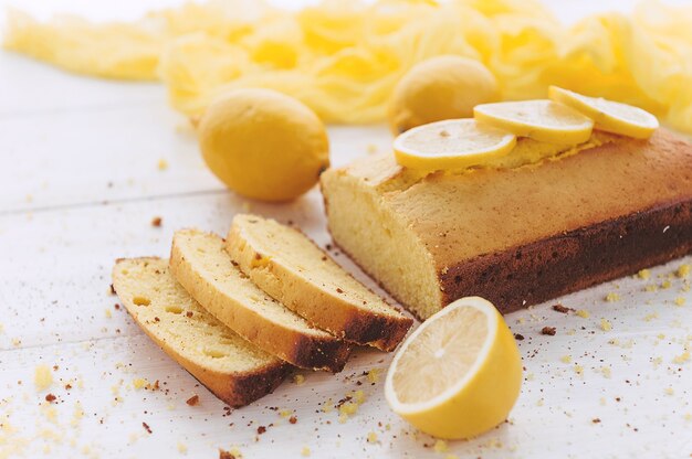 Pastel de limón con frutas sobre superficie de madera blanca