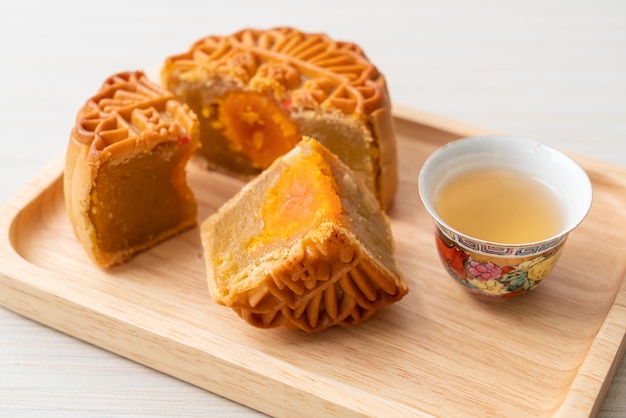 Pastel de luna chino durian y sabor a yema de huevo con té en placa de madera