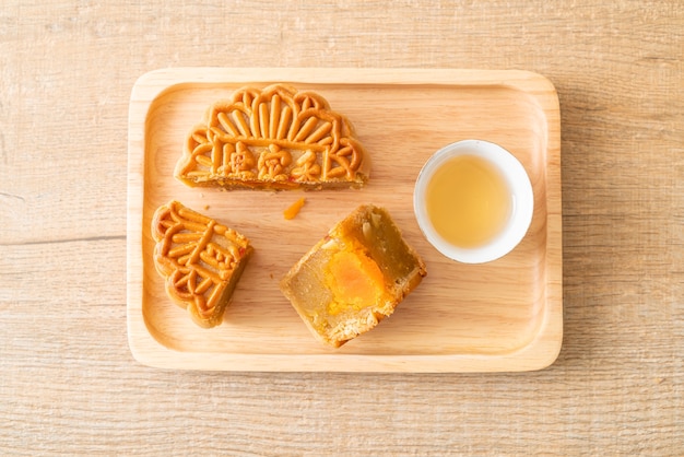 Pastel de luna chino durian y sabor a yema de huevo con té en placa de madera