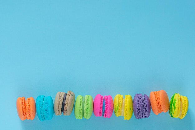 Pastel macaron o macaron sobre fondo turquesa desde arriba, galletas de almendras coloridas, colores pastel,