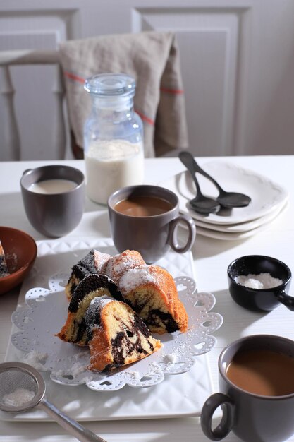 Pastel de mármol con café con azúcar en polvo y utensilios de cocina vintage, concepto de panadería blanca