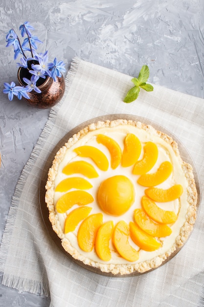 Pastel de melocotón y jarrón de cerámica con flores azules sobre gris