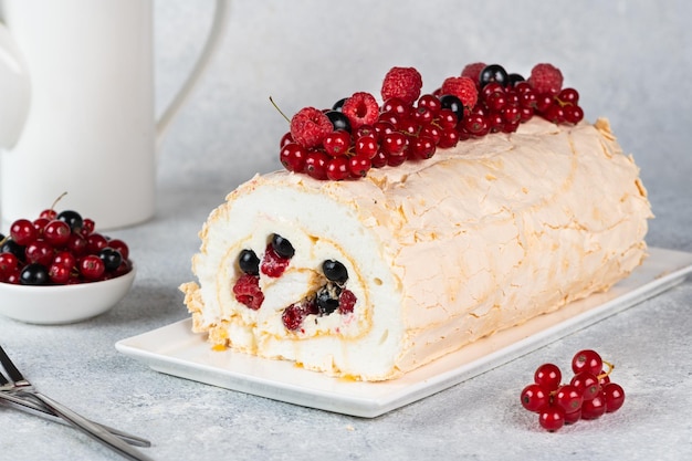 Pastel de merengue casero con crema batida de arándanos y frambuesas sobre fondo blanco Rollo de merengue Pastel Pavlova