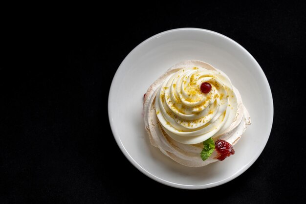 Pastel de merengue Pavlova con bayas frescas sobre fondo negro Pastel de merengue Pavlova