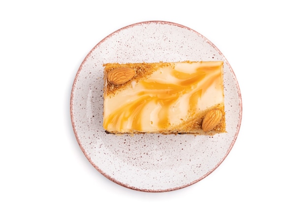 Pastel de miel con crema de leche, caramelo, almendras aislado sobre una superficie blanca