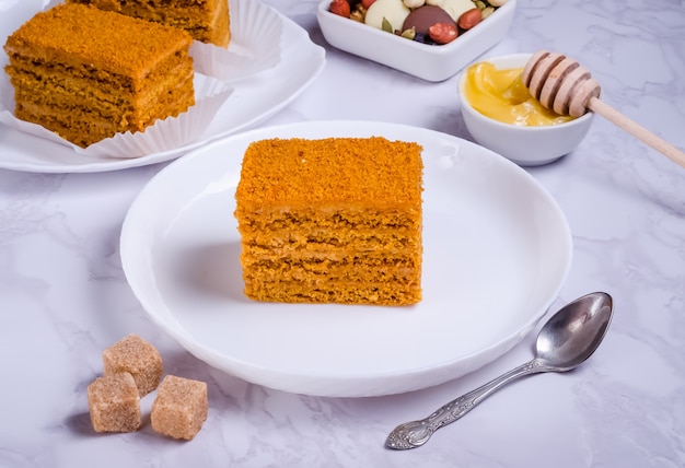 Pastel de miel con crema en un plato blanco sobre fondo de mármol