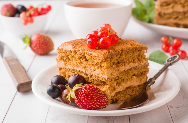 Pastel de miel con fresas, menta y grosellas y una taza de té