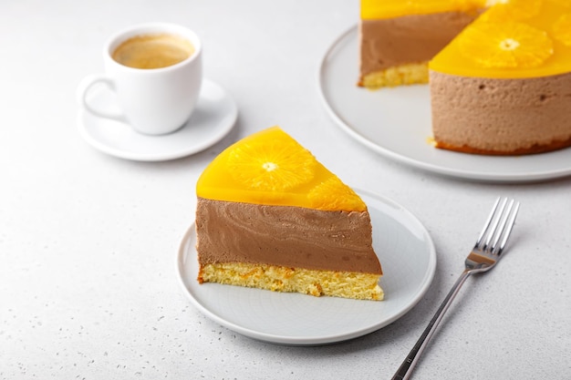 Pastel de mousse de chocolate y naranja con gelatina de base de galleta y círculos de naranja Pedazo de tarta de queso casera y una taza de café Postre tradicional de vacaciones Primer plano de enfoque selectivo