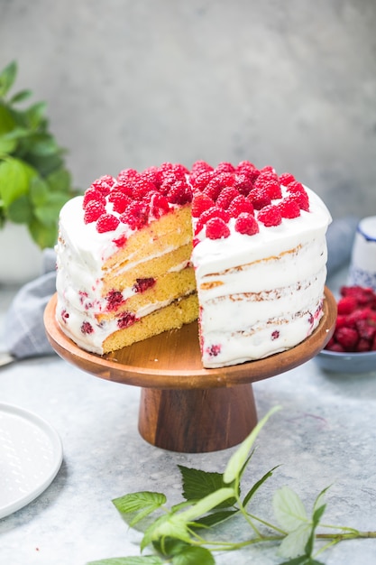 Pastel con mousse de crema y relleno de frambuesa sobre soporte redondo