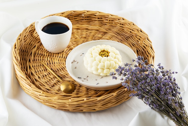 Pastel de mousse con una taza de café y un ramo de lavanda en una bandeja