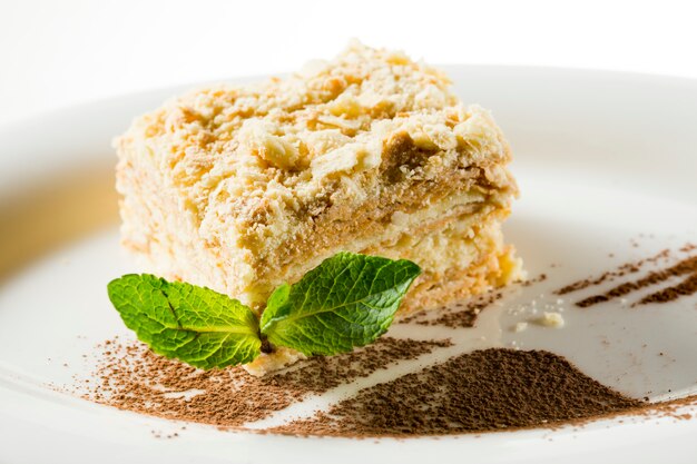 Pastel Napoleón con una hoja de menta en un plato decorado con chocolate