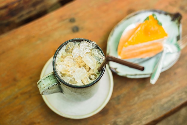 Pastel de naranja con café helado en la mesa de madera