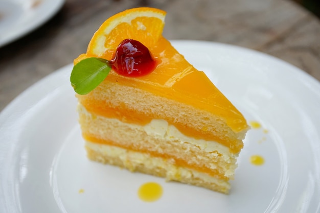 Pastel de naranja con relleno de naranja y cereza en la mesa de madera