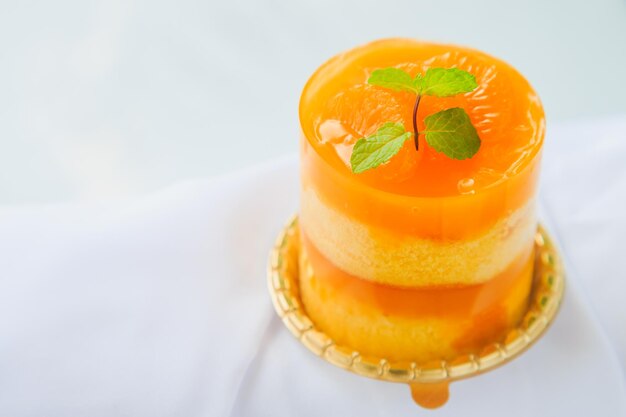 Un pastel de naranja con topping de narenja y menta en una mesa blanca