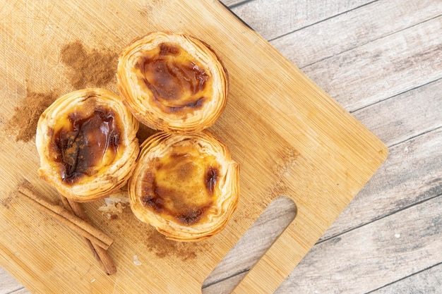 Pastel de nata o pastel de belem de PortugalxTres postres en la tabla de corte de madera