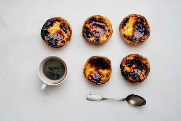 Pastel de nata. Postre tradicional portugués, tarta de huevo con taza de café sobre fondo de mármol. Vista superior