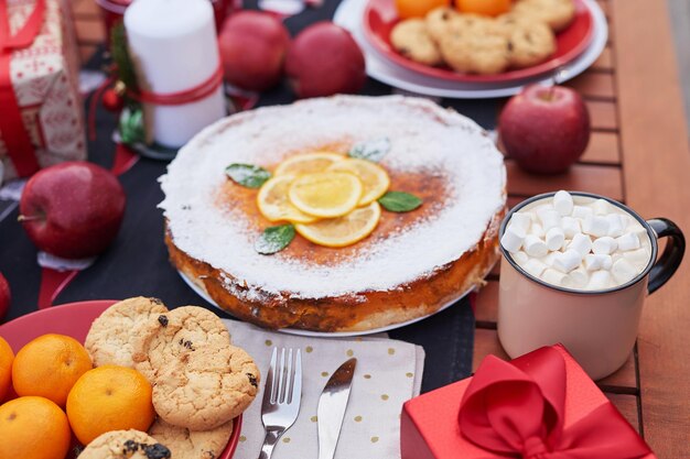 Pastel de Navidad, cacao con malvaviscos y mesa. Fondo de árbol de Navidad. Furgoneta remolque móvil, casa móvil, terraza. Celebración de Año Nuevo. Vacaciones de invierno. Mañana de Navidad.