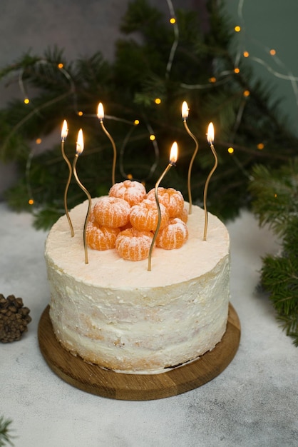 Pastel de navidad casero con velas de ramas de abeto sobre fondo gris