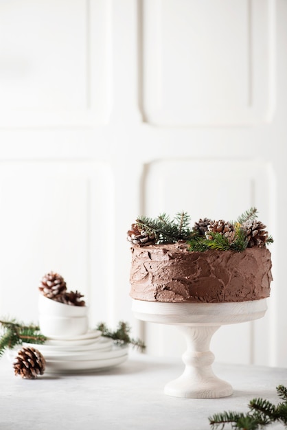 Foto pastel de navidad con chocolate decorado con piñas y pino sobre fondo claro, imagen de enfoque selectivo