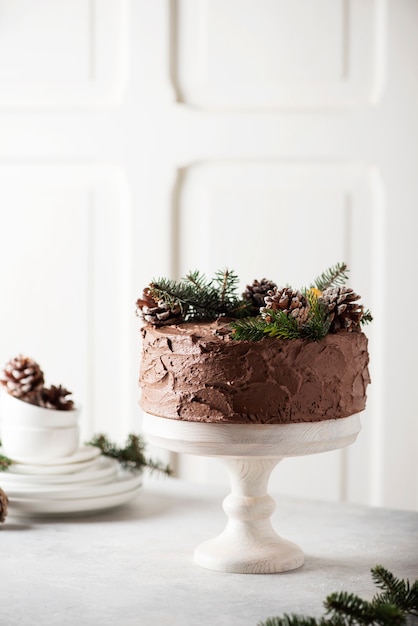 Foto pastel de navidad con chocolate decorado con piñas y pino sobre fondo claro, imagen de enfoque selectivo