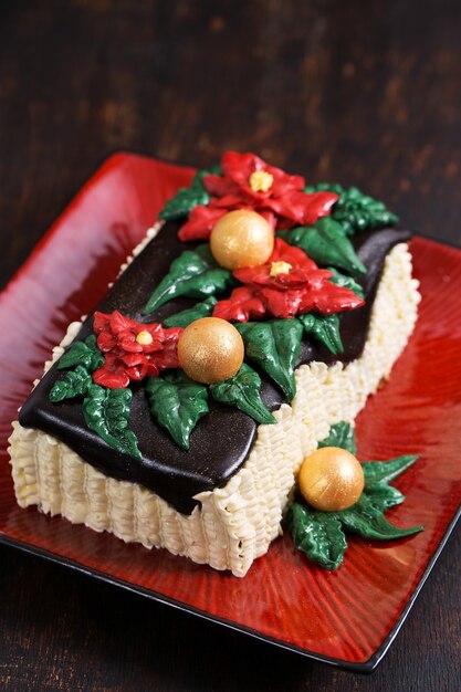 Pastel de Navidad con flores de nochebuena rojas y bolas doradas