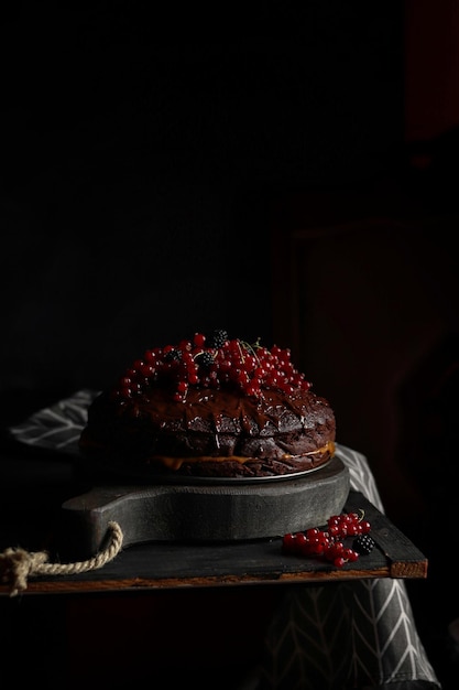 Un pastel negro con bayas rojas sobre una superficie de piedra negra