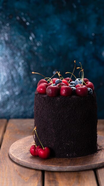 Pastel oscuro con bayas encima Un pastel decorado con arándanos y cerezas