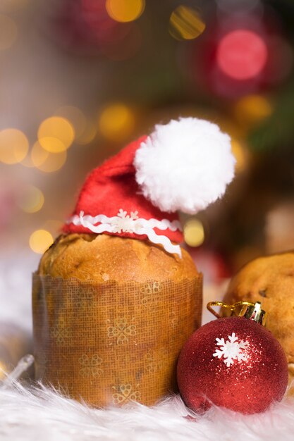 Pastel-panettone italiano tradicional con sombrero de Santa Claus. Fondo borroso de vacaciones de invierno